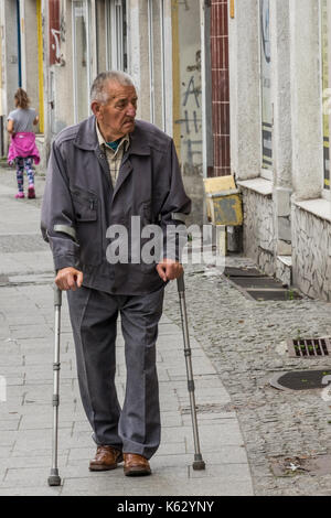 Bydgoszcz, Polonia - Agosto 2017 : vecchio disabilitato uomo a camminare con le stampelle per strada in città Foto Stock