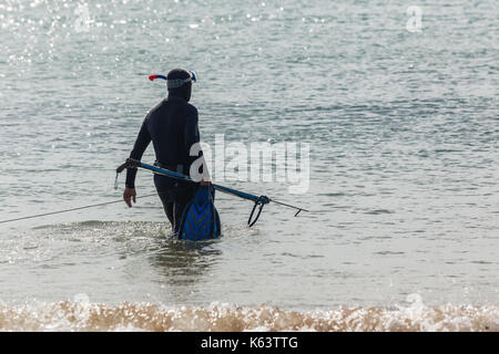 Sommozzatore in piena muta andando non identificato la pesca subacquea da beach ocean voce. Foto Stock