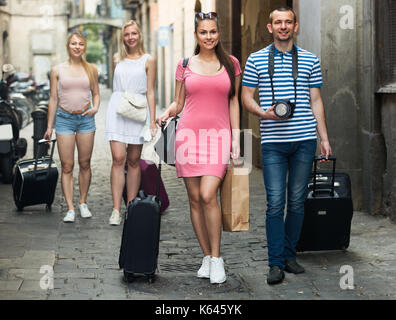 Ritratto di felice coppia turisti tenendo a piedi e trascinando valigie in città nel giorno di agosto Foto Stock