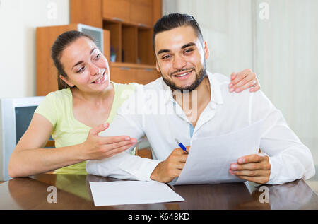 Sorridente coppia europea per discutere i termini del contratto a casa Foto Stock