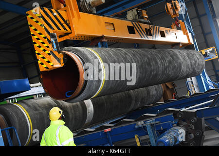 Un tubo di acciaio è rivestito in calcestruzzo in wasco rivestimento vegetale sull'isola ruegen, Germania, 11 settembre 2017. Il peso di calcestruzzo rivestimento è necessario fornire le tubazioni con una sufficiente stabilità sul fondo del mare. wasco·s rivestimento vegetale in mukran fornirà rivestimenti in calcestruzzo servizi per circa 90.000 tubi; le tubazioni rivestite saranno portavamo ad interim storages lungo la pipeline proiettata dalla nave. photo: Stefan Sauer/dpa Foto Stock