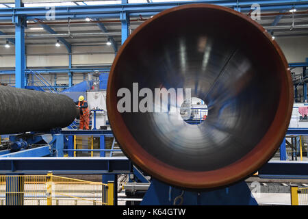 Un tubo di acciaio è rivestito in calcestruzzo in wasco rivestimento vegetale sull'isola ruegen, Germania, 11 settembre 2017. Il peso di calcestruzzo rivestimento è necessario fornire le tubazioni con una sufficiente stabilità sul fondo del mare. wasco·s rivestimento vegetale in mukran fornirà rivestimenti in calcestruzzo servizi per circa 90.000 tubi; le tubazioni rivestite saranno portavamo ad interim storages lungo la pipeline proiettata dalla nave. photo: Stefan Sauer/dpa Foto Stock