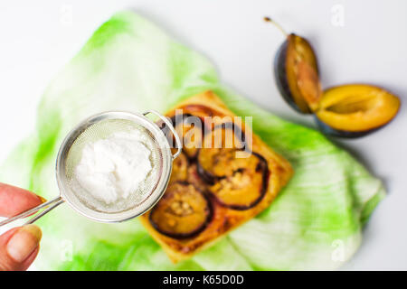 Aggiunta di zucchero alla prugna dolce fetta di torta Foto Stock