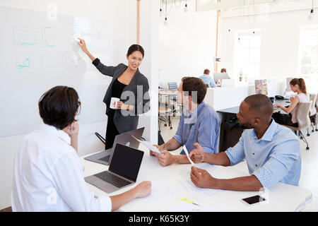 La donna rivolta a lavagna nel corso di una riunione in un ufficio Foto Stock