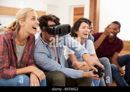 Amici a giocare giochi per computer con la realtà virtuale auricolare Foto Stock