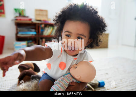 Happy Baby girl gioca con bambola in sala giochi Foto Stock