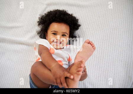 Tettuccio di colpo di sorridente bambina giacente sul letto Foto Stock