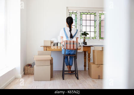 Vista posteriore della donna in esecuzione dal Business Home spedire delle merci Foto Stock
