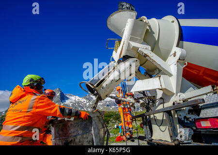 I lavoratori della società Swiss Helicopters stanno preparando il carico per il trasporto del calcestruzzo in un cantiere in elicottero nelle montagne da B Foto Stock