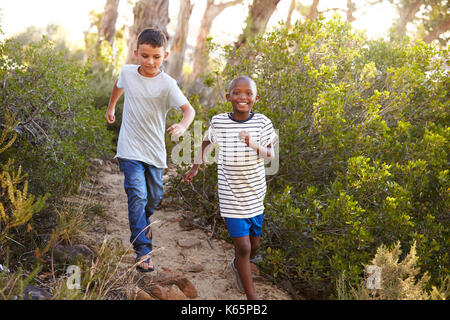 Due giovani sorridenti boys racing su un sentiero di bosco Foto Stock