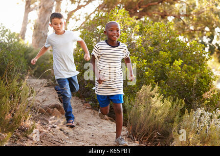 Due felici i ragazzi correre giù per un sentiero di bosco Foto Stock