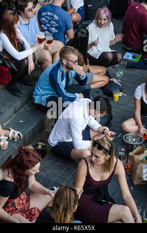 Guardando verso il basso su uomini e donne sedeva sul pavimento al di fuori di un pub di Camden Town. Foto Stock