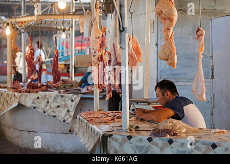 Fornitore del Kirghizistan vendita di carne a antigienico butcher stand al mercato alimentare di stallo nella città di Osh lungo la via della seta in Kirghizistan Foto Stock