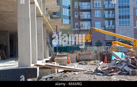 Una sporca, incompiuto mucchio di ghiaia accanto a travi di cemento e un lavoro giallo carrello Foto Stock