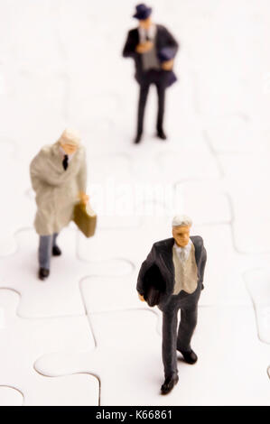 Business figurine in miniatura su puzzle Foto Stock