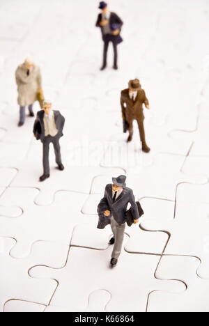 Business figurine in miniatura su puzzle Foto Stock