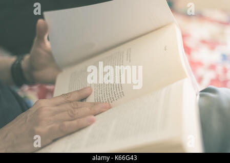 La donna la lettura del libro. Messa a fuoco selettiva, vicino. Croce trasformati con pellicola vintage effetto. Dai toni caldi. Foto Stock