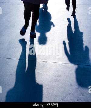 Ombre sfocate di madre con due bambini bimbi in esecuzione dopo il suo sul lungomare di estate Foto Stock