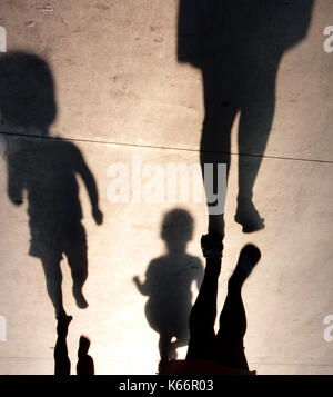 Ombre sfocate di madre con due bambini bimbi in esecuzione dopo il suo sul lungomare di estate Foto Stock