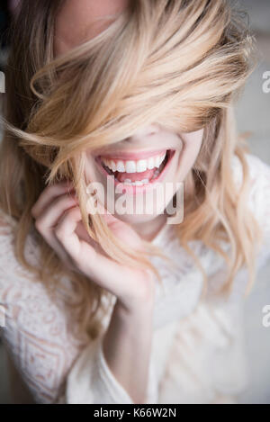 Ridendo donna caucasici che coprono gli occhi con i capelli Foto Stock