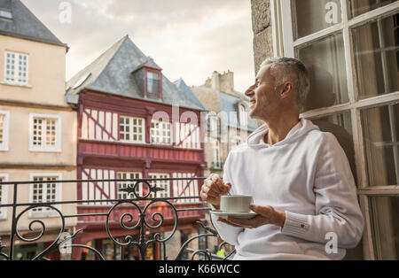 Uomo caucasico agitazione il caffè sul balcone in città Foto Stock