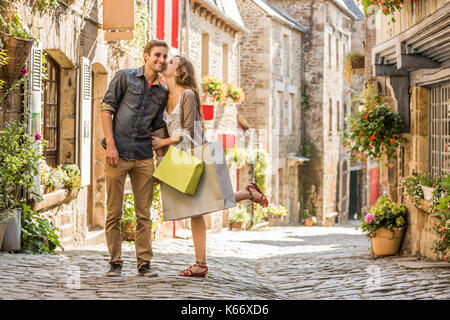 La donna caucasica con shopping bags baciare uomo in città Foto Stock