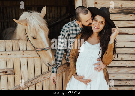 Uomo di baciare la donna sulla guancia vicino stabile Foto Stock