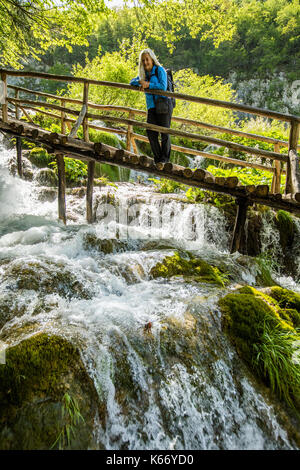 I vecchi donna caucasica sulla passerella di legno ammirando la cascata Foto Stock