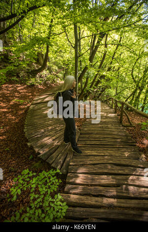 I vecchi donna caucasica camminando sul percorso di legno nella foresta Foto Stock