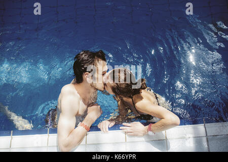 Coppia caucasica baciare in piscina Foto Stock