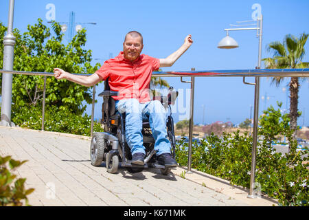 Uomo disabili su sedia elettrica godere al parco Foto Stock