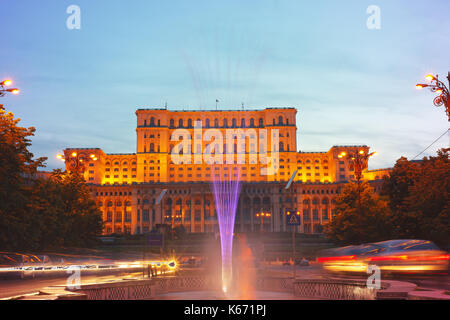 Liberty boulevard al crepuscolo con fontane illuminate guardando verso il palazzo del parlamento, il più amato e più odiato edificio in Romania. Foto Stock