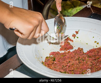 Lo chef femmina preparazione bistecca alla tartara in cucina con una salsa speciale in ristorant Foto Stock