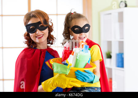 Donna e per suo figlio la figlia in costumi di supereroi. mamma e bambino pronto per la pulizia della casa. i lavori di casa e il servizio di pulizie. Foto Stock