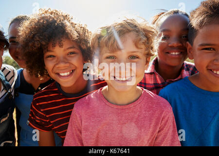 Close up pre-teen di amici in un parco di sorridere alla telecamera Foto Stock