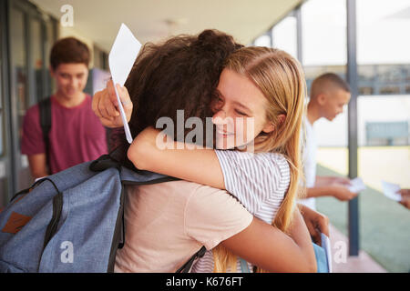 Due ragazze che celebra i risultati degli esami nel corridoio della scuola Foto Stock