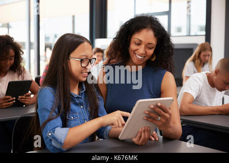 Docente aiutare teenage schoolgirl con computer tablet Foto Stock