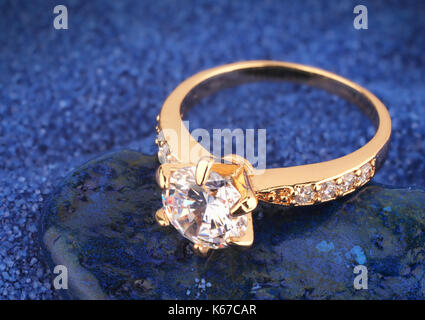 Golden jewelery anello con diamante su sfondo blu Foto Stock