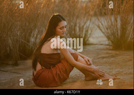 Bella donna seduta sulla spiaggia, Thailandia Foto Stock