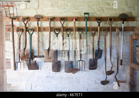 Attrezzi da giardino ordinatamente disposti su scaffalature Foto Stock