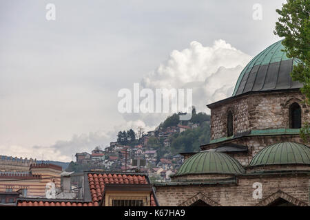 Moschea, dal centro città di Sarajevo, Bosnia ed Erzegovina, con un tipico sfondo di Sarajevo con piccole case su una collina, durante una torbida af Foto Stock