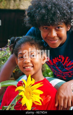 Giovani sorridente felicemente tenendo un girasole mostrano che hanno coltivato Foto Stock