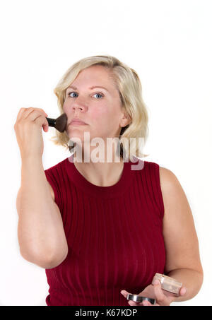 Donna con faccia rossa mette in polvere per il trucco da un caso di studio Foto Stock