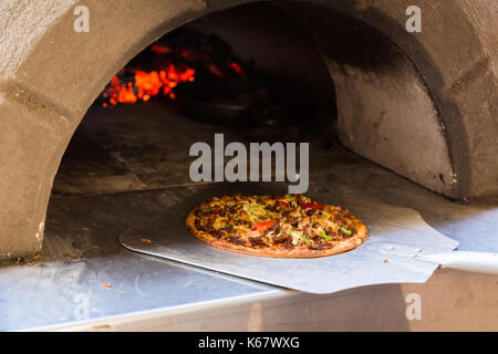 Rimozione di una pizza dal forno da pizza Foto Stock