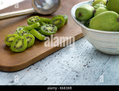 Bacche di kiwi affettato e tutto disposto su una tavola di legno messa a fuoco selettiva con spazio di copia Foto Stock