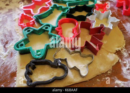 Varie Il Natale cookie cutters bloccato in zucchero pasta biscotto su un tavolo fiorito. Foto Stock