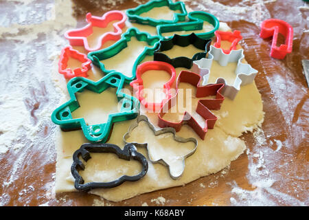 Varie Il Natale cookie cutters bloccato in zucchero pasta biscotto su un tavolo fiorito. Foto Stock