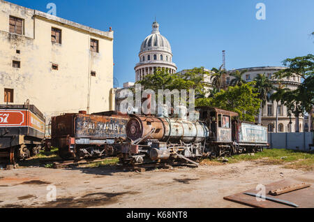 Scrapyard dietro la mitica capitale nazionale edificio nel centro di Avana, capitale di Cuba, con derelitti, arrugginimento locomotore ferroviario motori Foto Stock