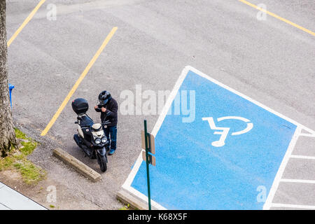 Ile D'Orleans, Canada - 1 Giugno 2017: vista aerea di biker uomo in motocicletta nel parcheggio con persone con disabilità bollino blu a riposo in autostrada, strada Foto Stock