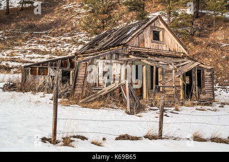 Casa diroccata che mostra anni di abbandono nel sole di sera Foto Stock